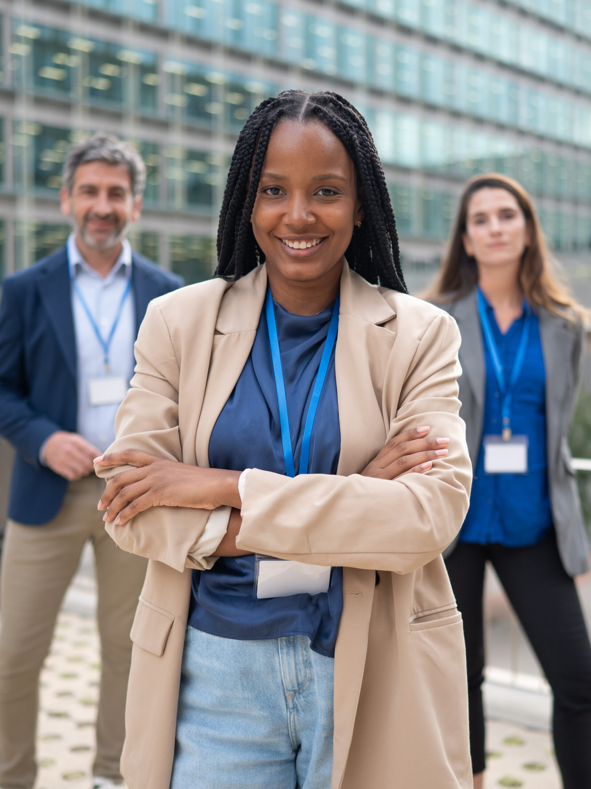 Smiling Black businesswoman leading diverse corporate group with ID badges standing outdoors